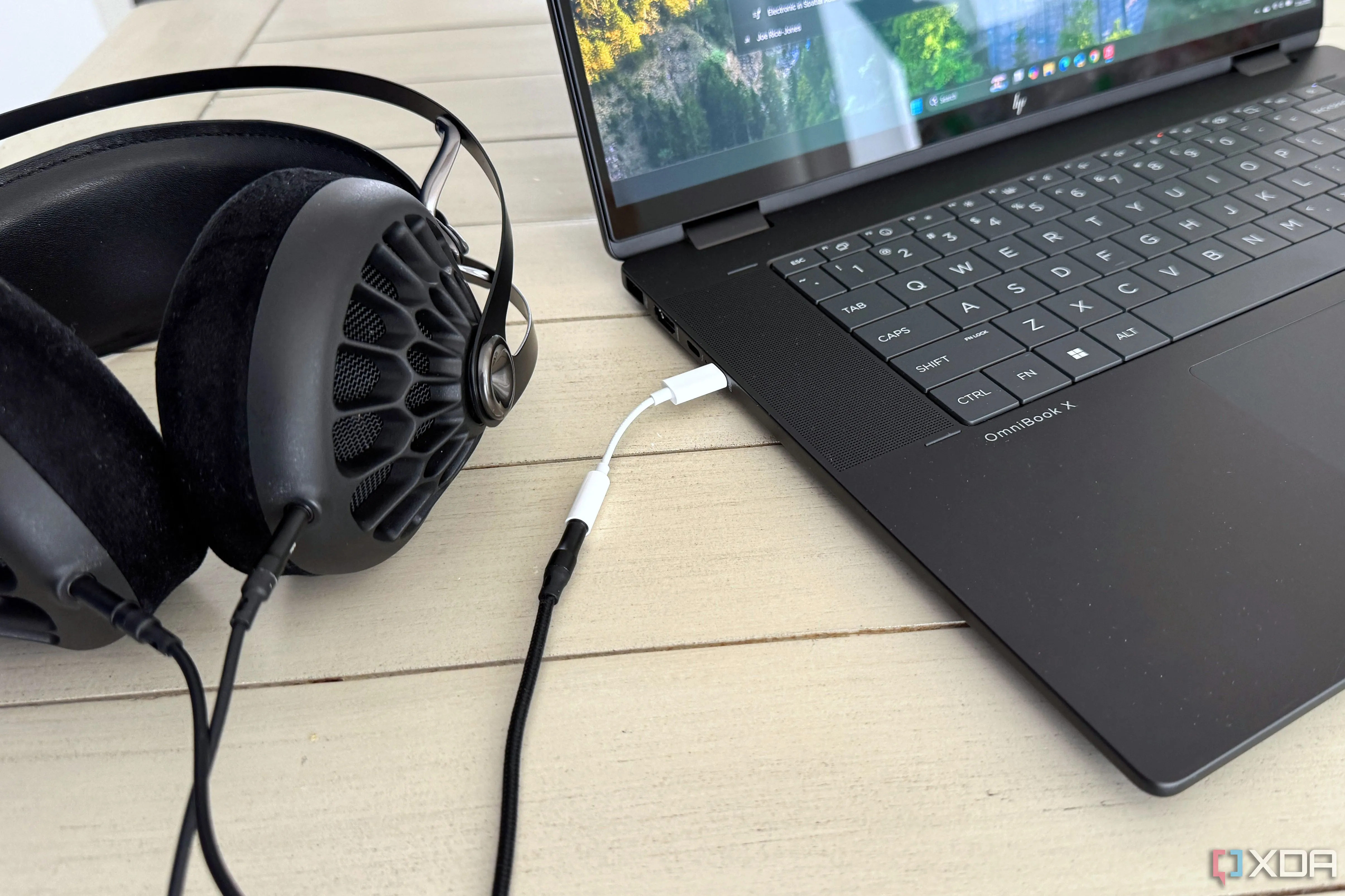 Bộ chuyển đổi Apple USB-C sang 3.5mm được cắm vào máy tính xách tay, minh họa việc sử dụng thực tế để cải thiện chất lượng âm thanh.