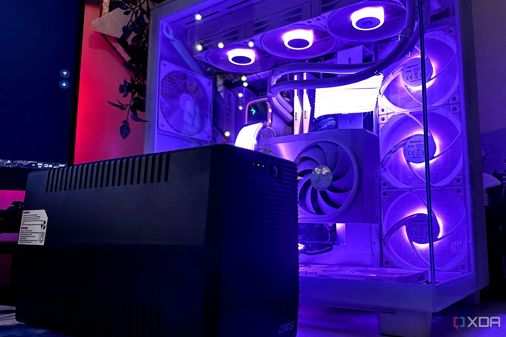Bộ lưu điện UPS màu đen đặt cạnh thùng máy tính gaming, minh họa cho tầm quan trọng của nguồn điện dự phòng cho PC.