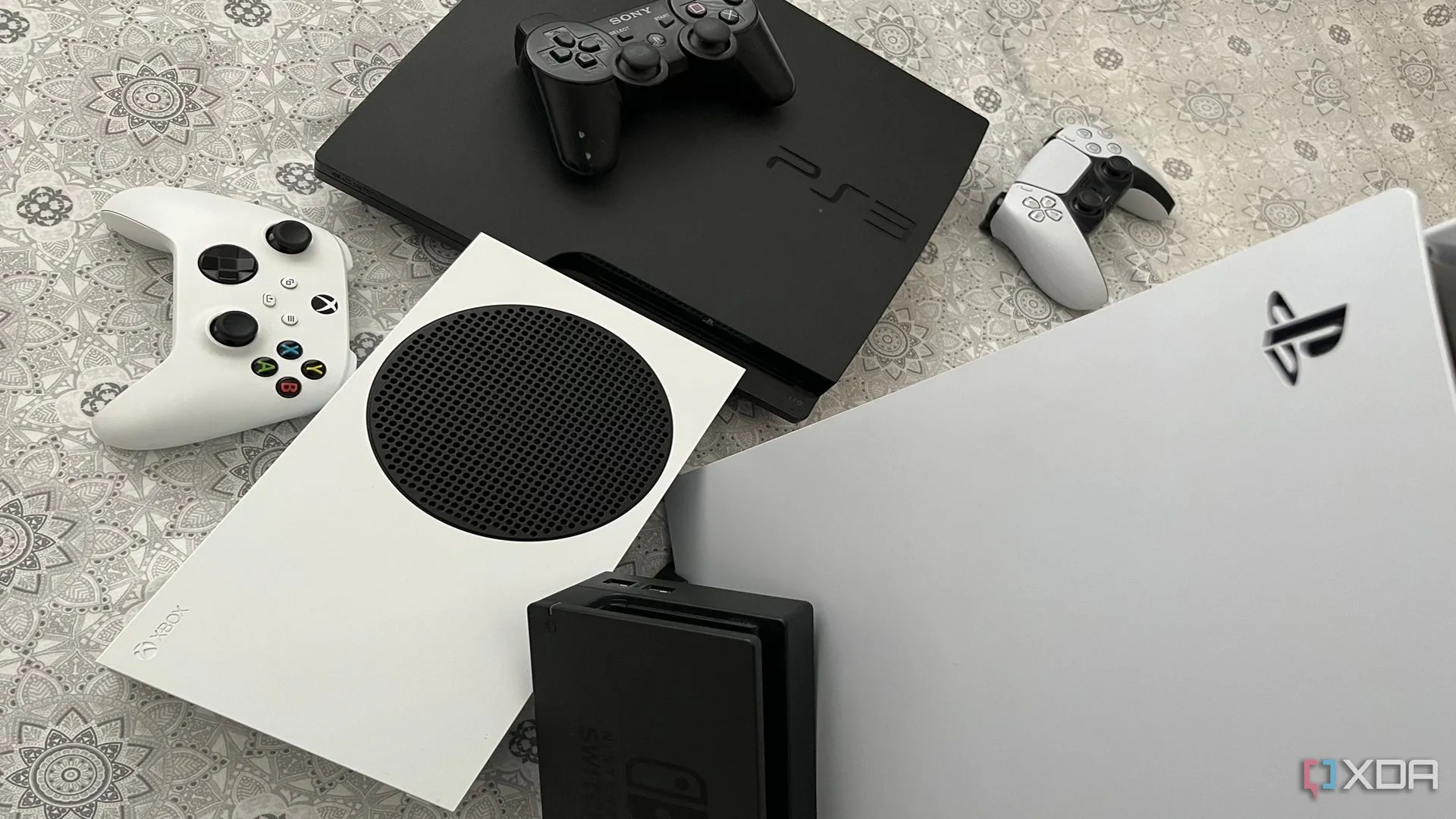 Bộ sưu tập các console game bao gồm PlayStation 5, Xbox Series X và Nintendo Switch Dock, thể hiện sự đa dạng phần cứng.