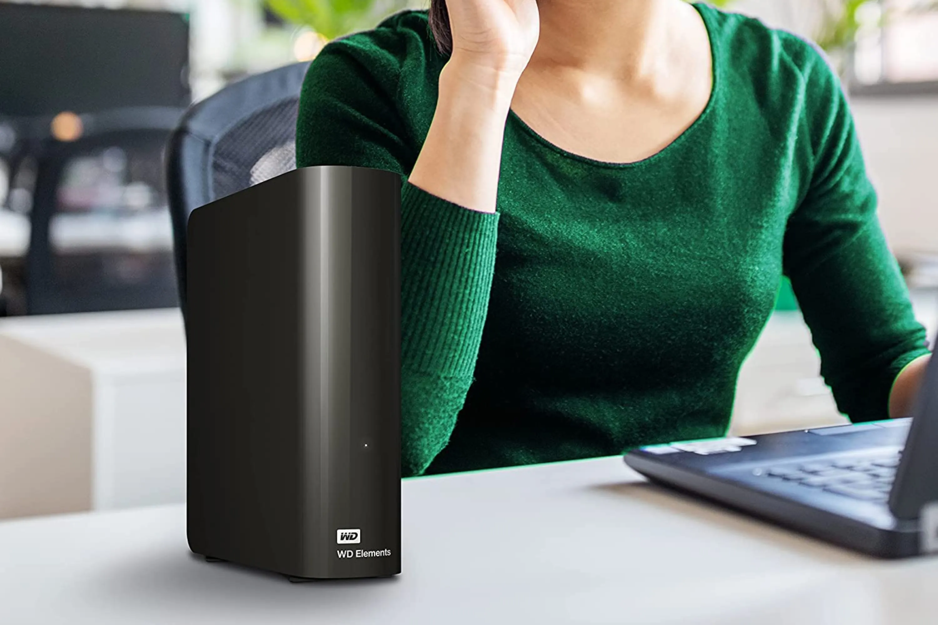 Hình ảnh ổ cứng WD Elements Desktop 14TB được đặt trên bàn làm việc cùng người dùng
