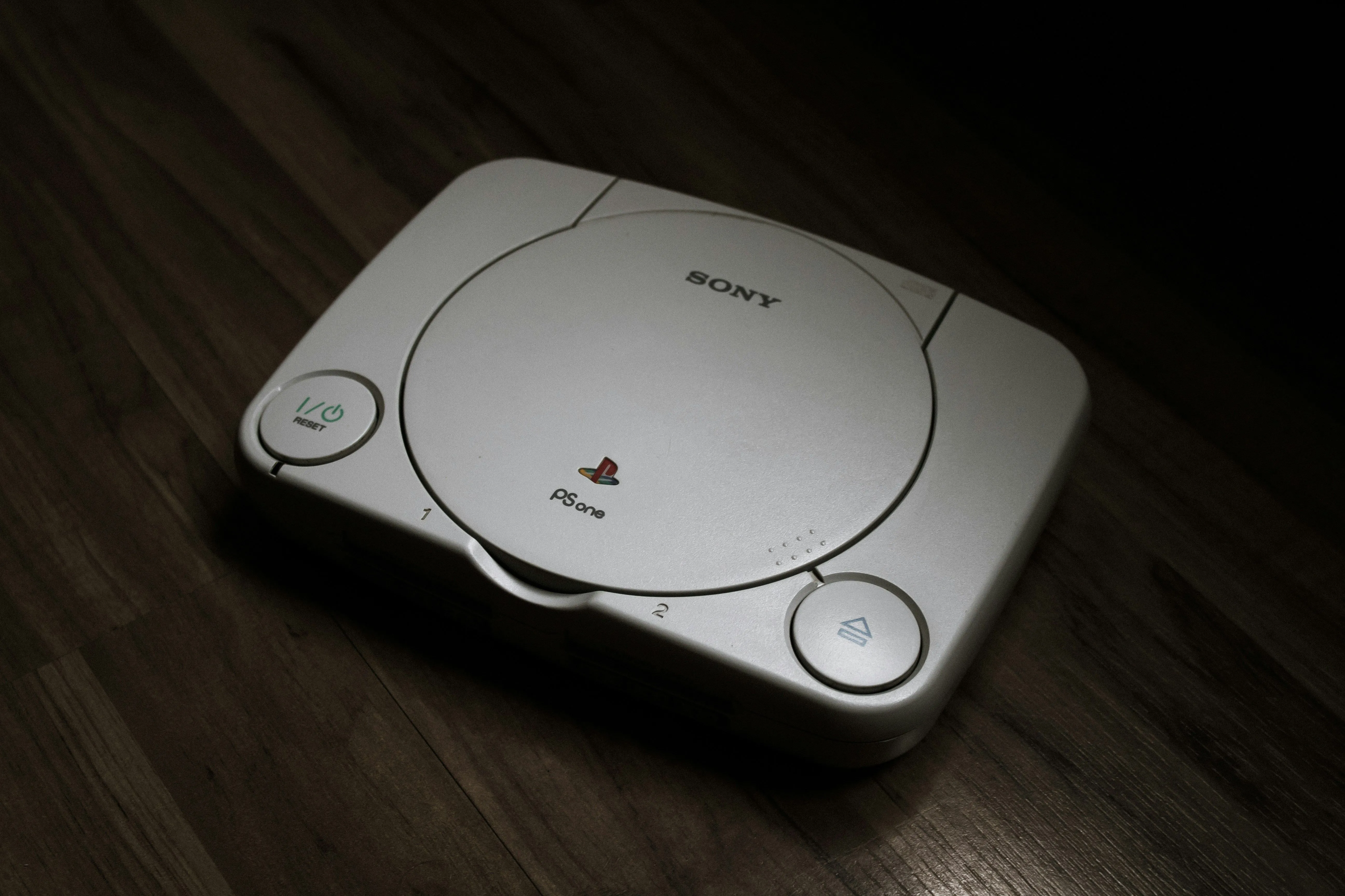 Máy chơi game PlayStation 1 đặt trên sàn gỗ, minh chứng cho sự phát triển của console