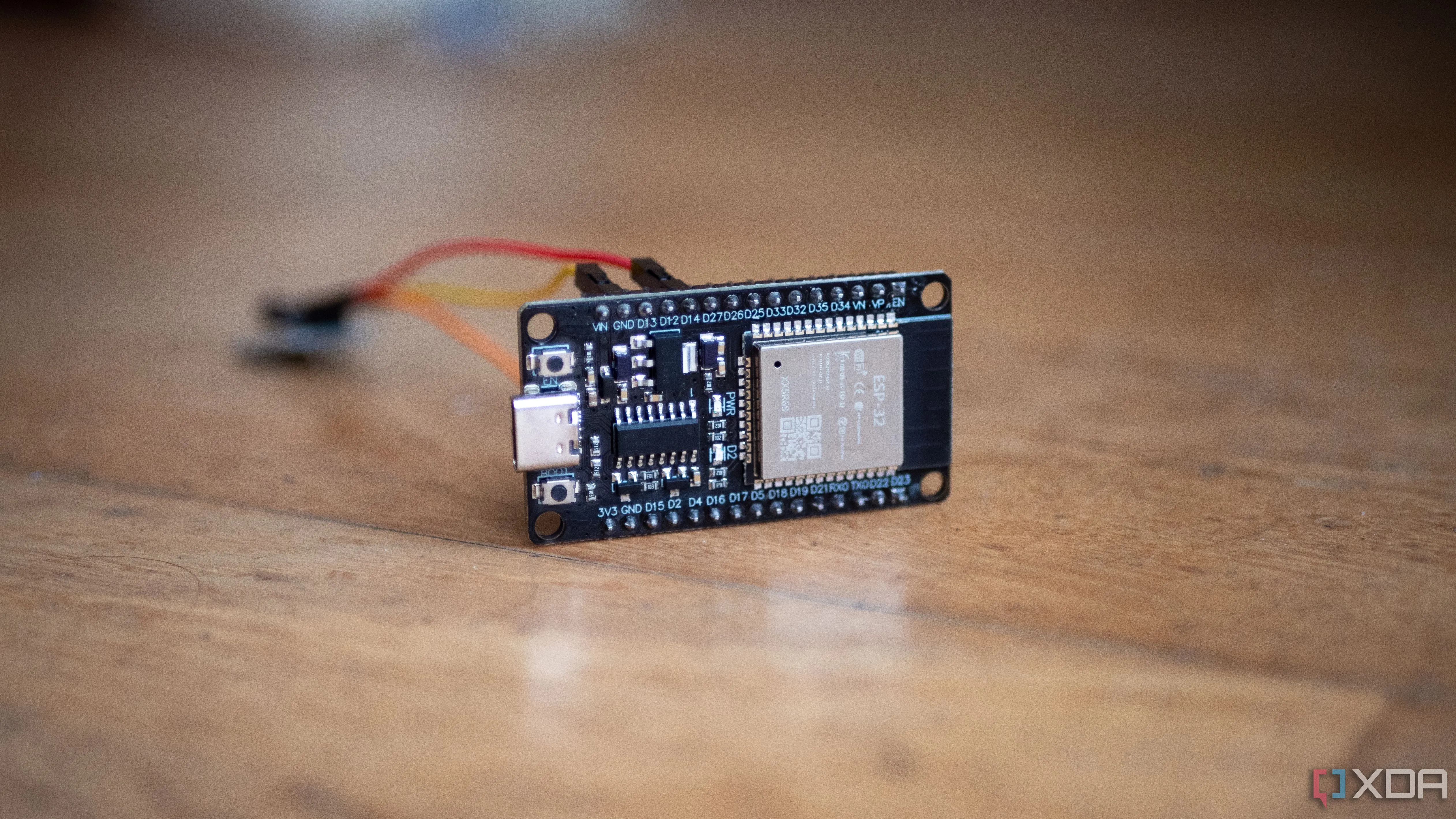 Một bo mạch ESP32 được kết nối với cảm biến rung bằng dây nhảy trên bàn