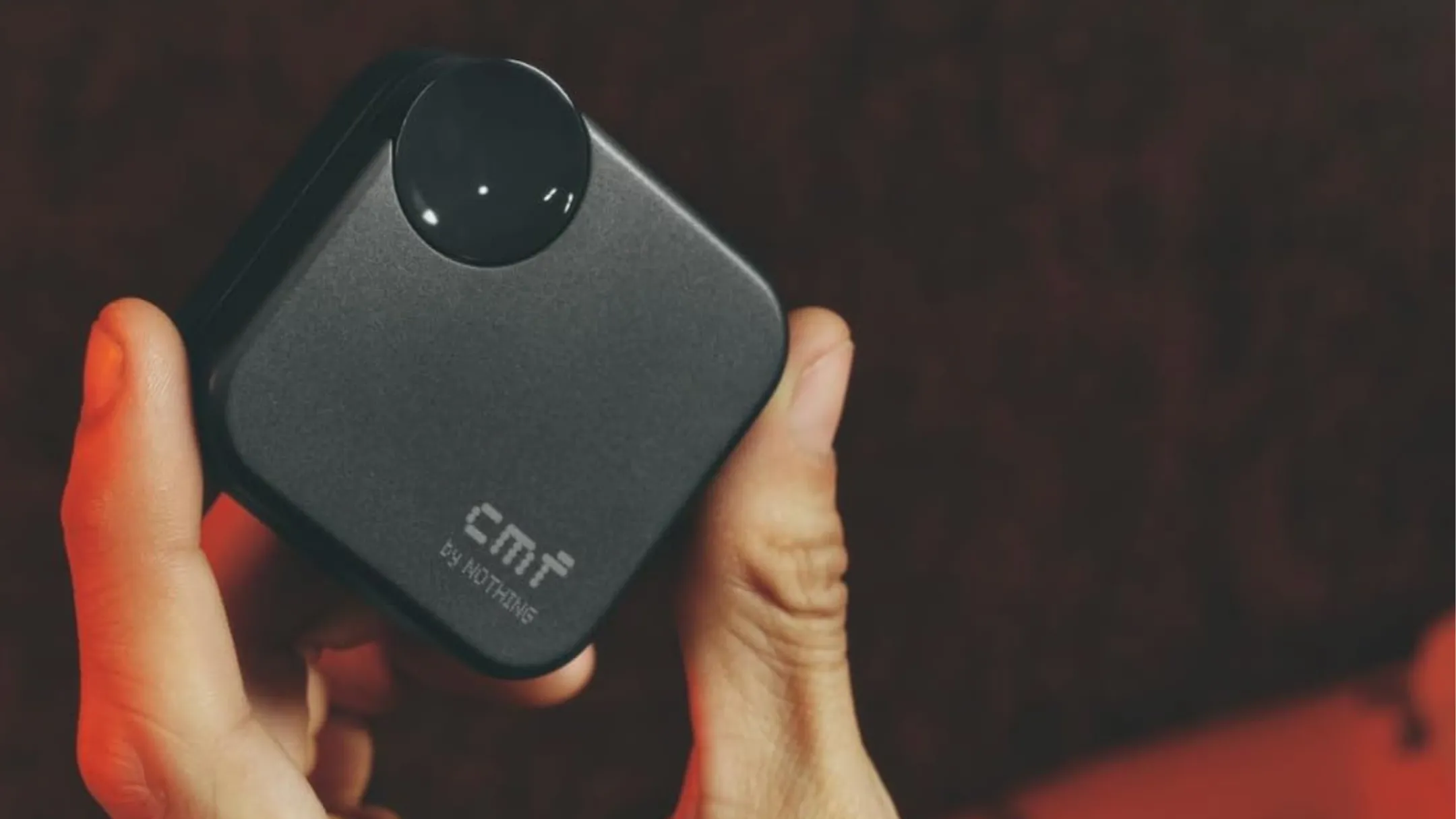 Người dùng cầm tai nghe không dây CMF Buds 2a màu đen và hộp sạc