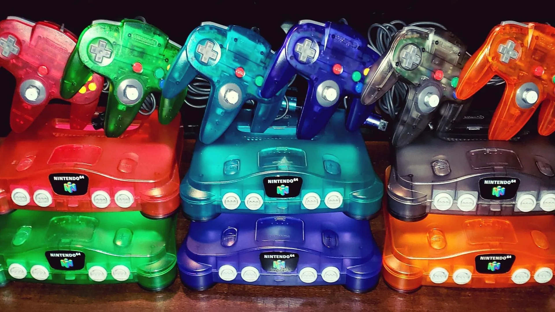 Nhiều máy chơi game Nintendo 64 với các màu sắc và vỏ trong suốt khác nhau được trưng bày.